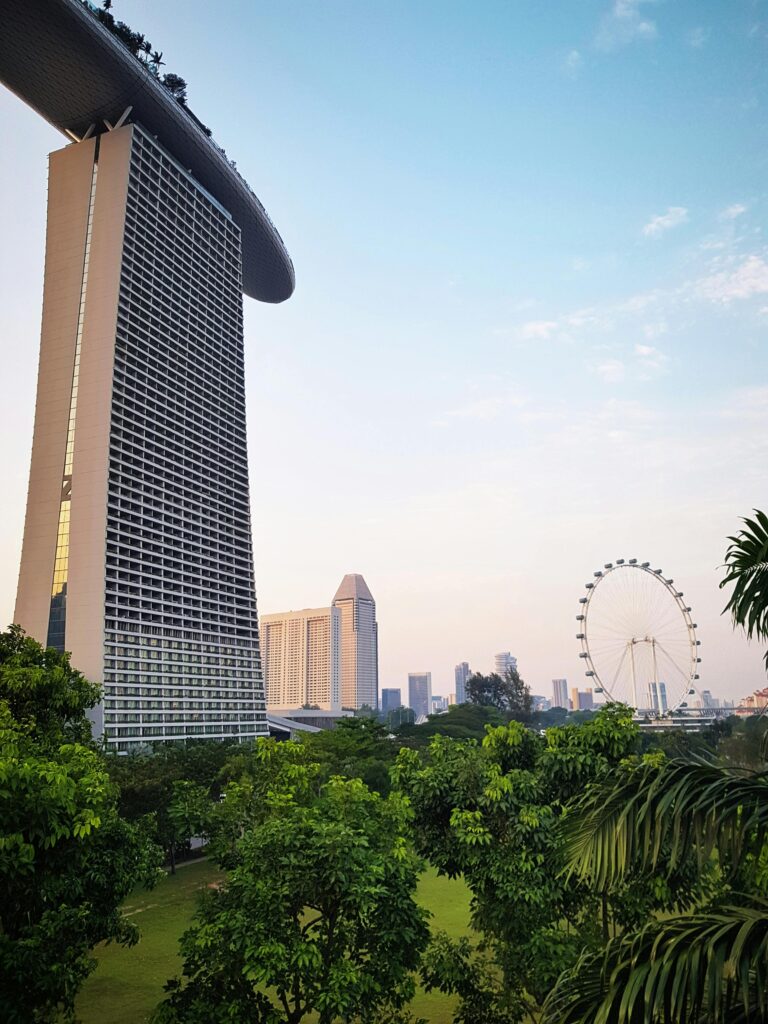 View of Marina Bay Sands against Singapore skyline with lush greenery in the foreground.